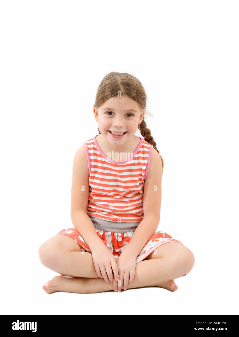Young girl sat on floor looking at camera on isolated white background Stock Photo