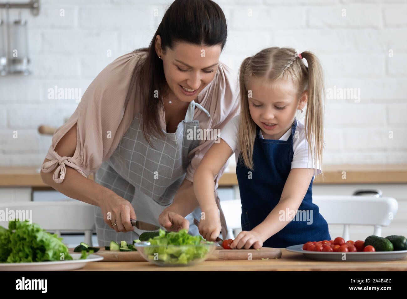 Caring mother teaching little daughter to cook salad Stock Photo