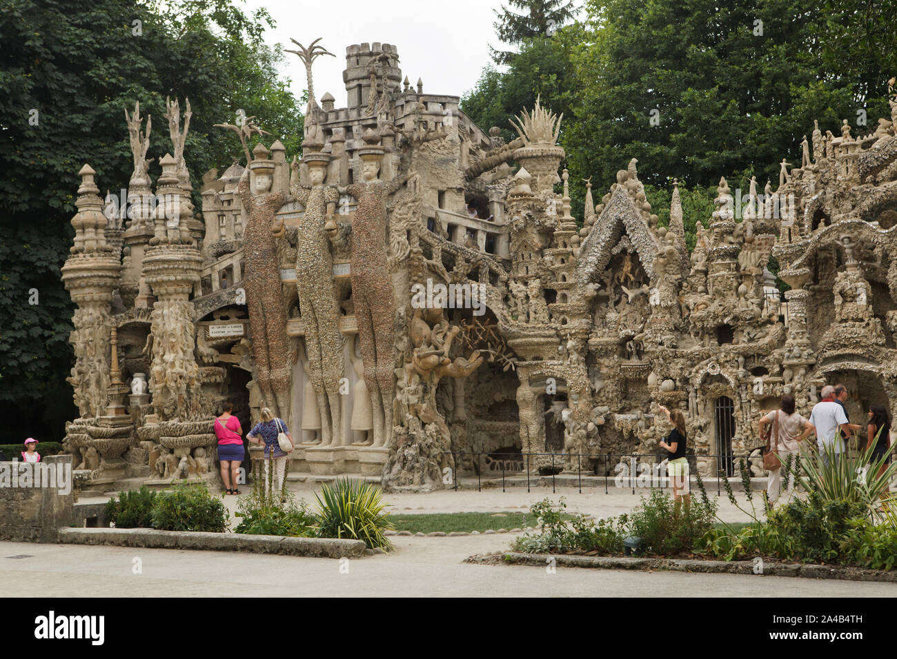 Visitors in front of the Ideal Palace (Le Palais idéal) designed by French postman Ferdinand Cheval and build from 1876 to 1912 in Hauterives, France. Roman dictator Julius Caesar, Celtic king Vercingetorix and Greek mathematician and physicist Archimedes are depicted from left to right as the Three Giants on the east facade. ATTENTION: This image is a part of a photo essay of 36 photos featuring the Ideal Palace (Le Palais idéal). Stock Photo