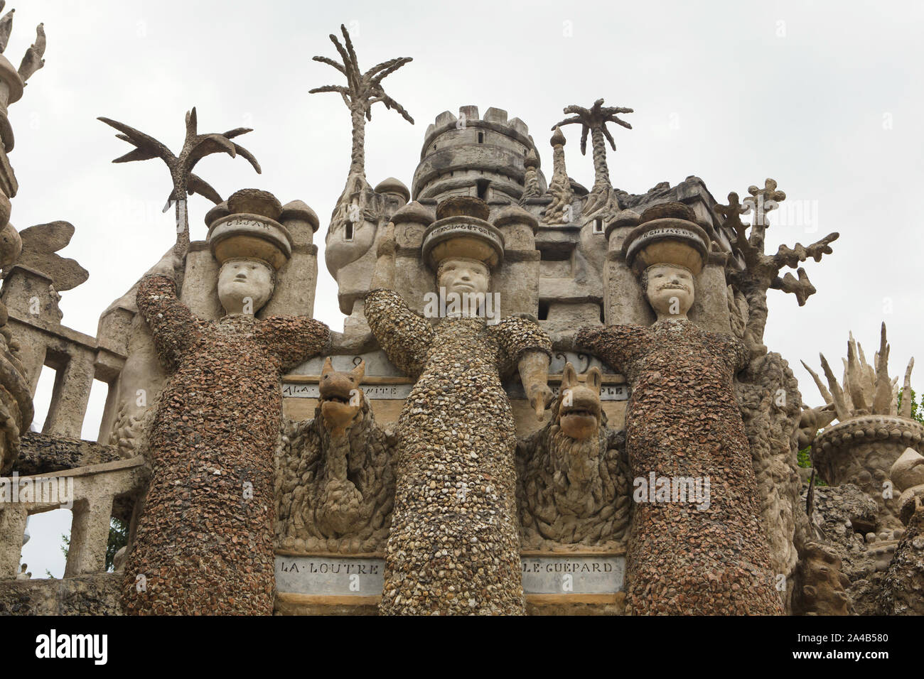 Huge statues of the Three Giants on the east facade of the Ideal Palace (Le Palais idéal) designed by French postman Ferdinand Cheval and build from 1876 to 1912 in Hauterives, France. Roman dictator Julius Caesar, Celtic king Vercingetorix and Ancient Greek mathematician and physicist Archimedes are depicted from left to right as the Three Giants. An otter and a cheetah are depicted bellow between the giants. ATTENTION: This image is a part of a photo essay of 36 photos featuring the Ideal Palace (Le Palais idéal). Stock Photo