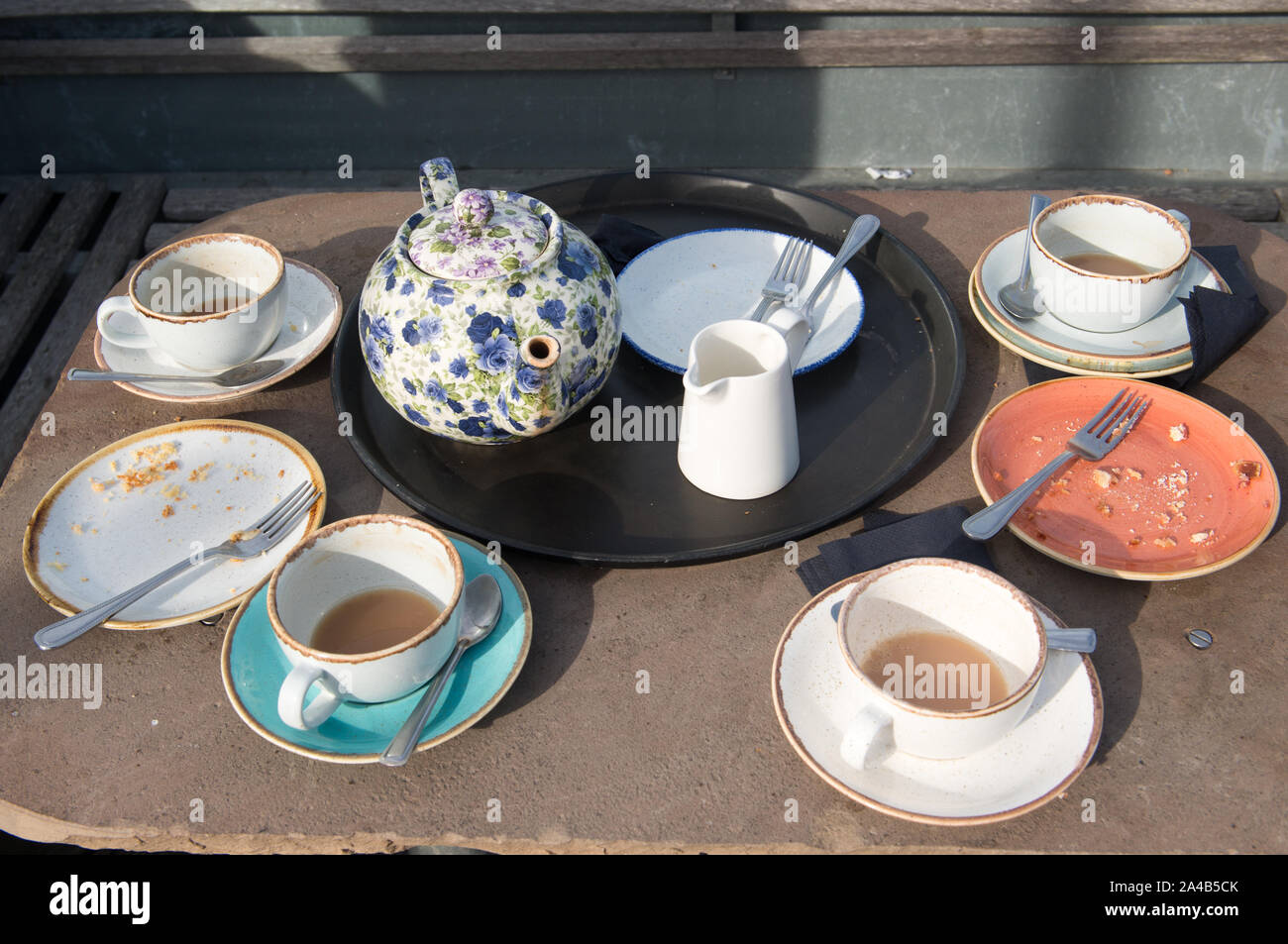 Floral teapot and used cups and saucers left on an outdoor cafe table