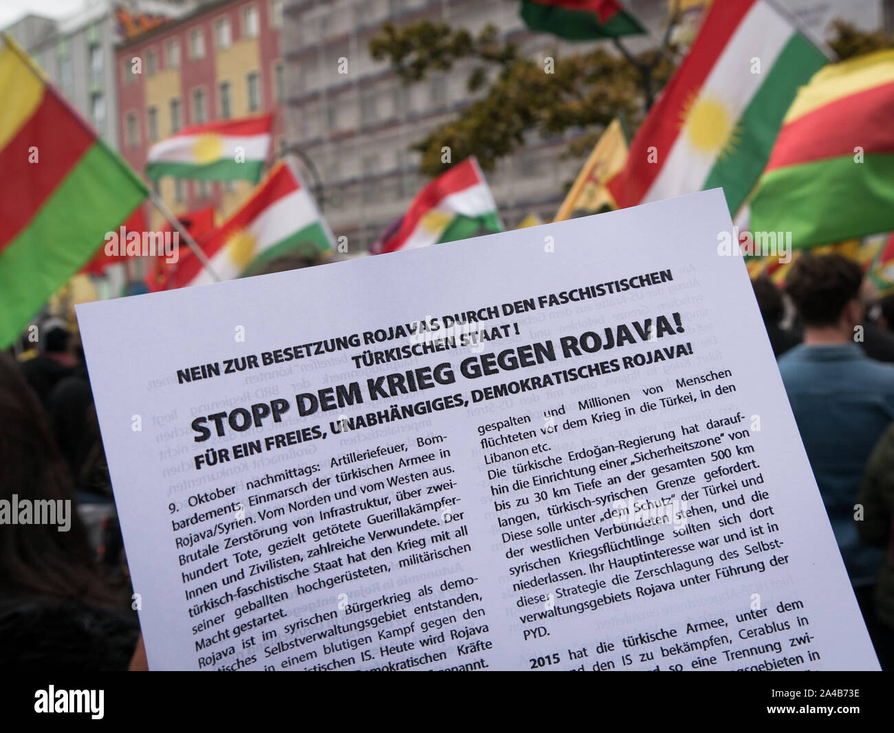 Demostration and protest against Turkish offensive in Syria against the Kurds, flyer calling for end of war in rojava, ypg and kurdish flags in back Stock Photo