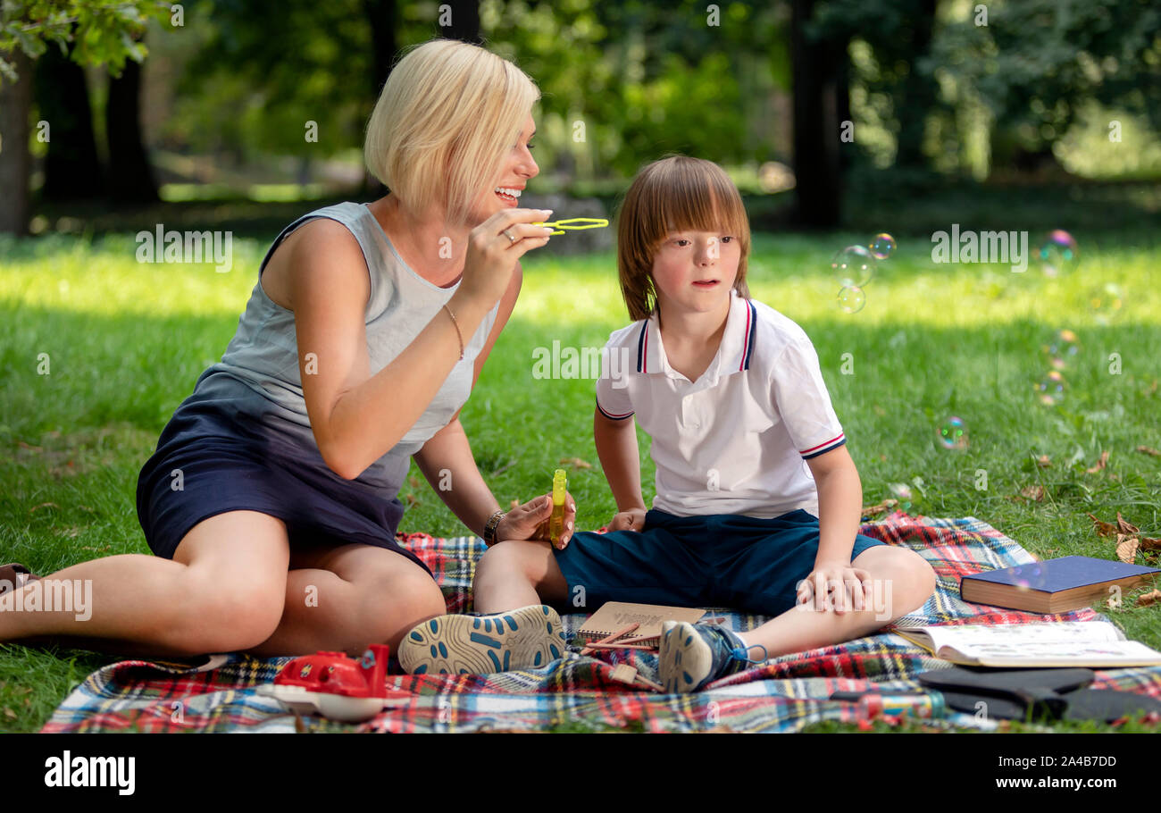 Mentally challenged boy watches the soap bubbles blown by his mom with interest Stock Photo