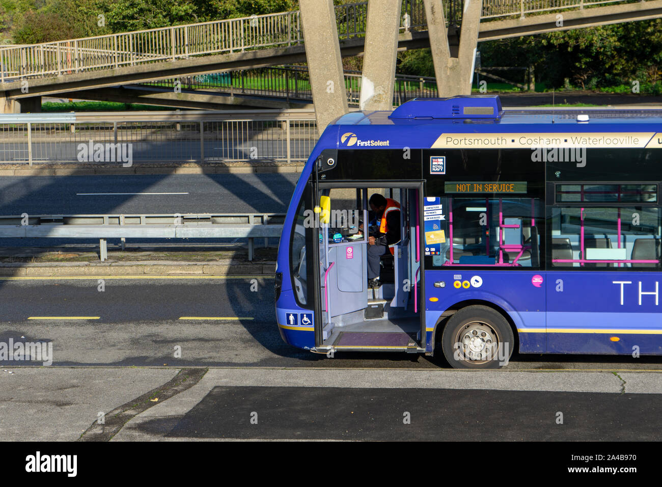 A bus driver at the wheel of his bus waiting at a bus stop Stock Photo