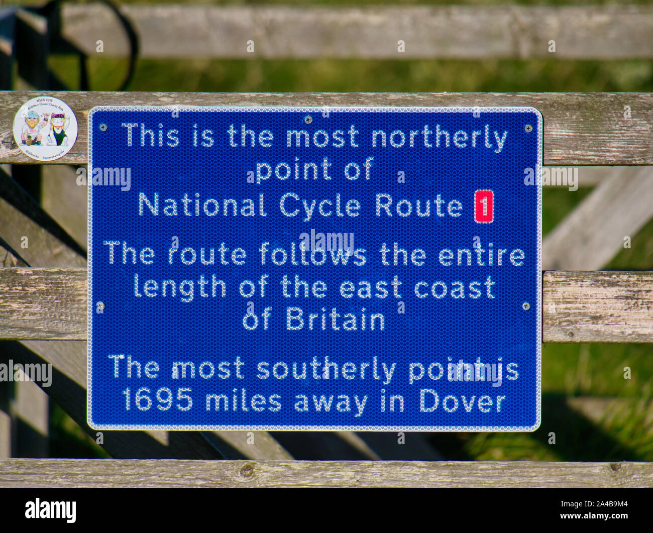 A blue sign marking the most northerly point of UK National Cycle Route 1, in Skaw on the island of Unst in Shetland, Scotland, UK. Stock Photo