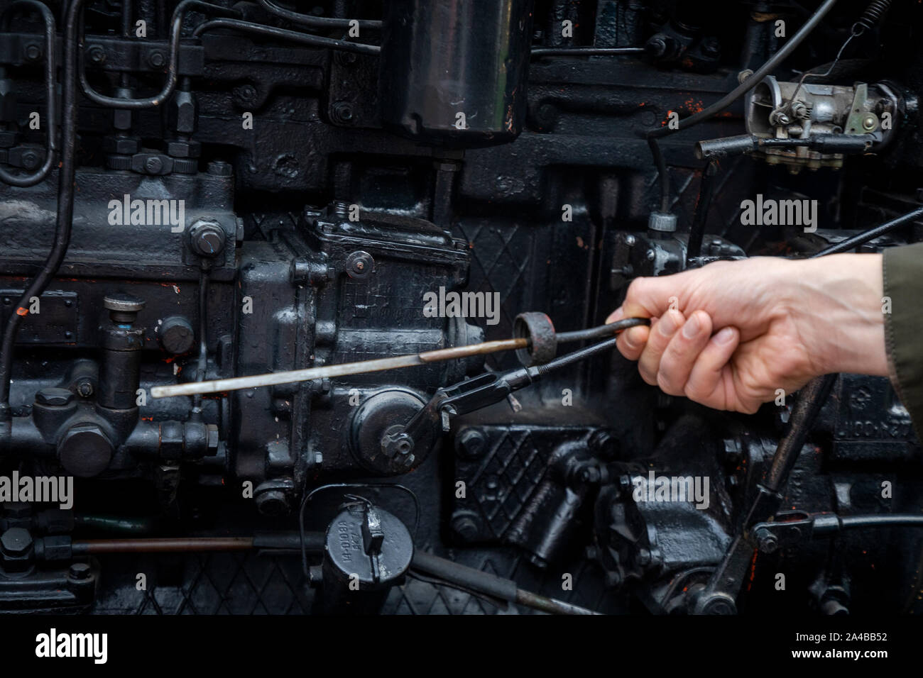 A man checks an oil level in the engine of Russian caterpillar tractor T-74 in Moscow, Russia Stock Photo