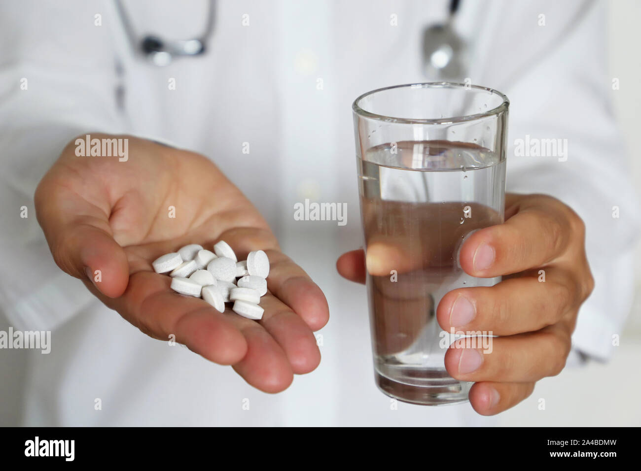 Pills and glass of water in hands of doctor, physician giving medication in white tablets. Concept of dose of drugs, medical exam, pharmacist Stock Photo