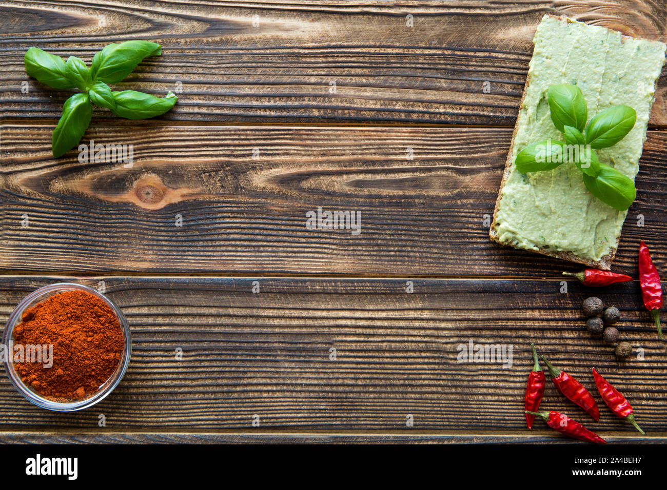 Avocado hummus with basil leaves and sweet paprika on brown wooden table, space for text, free space. Stock Photo