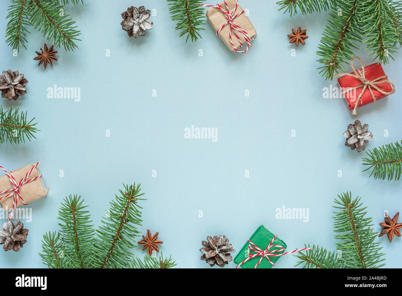 Christmas flat lay background. frame made of fir branches, decorations, gift boxes and pine cones on blue background. top view with copy space Stock Photo