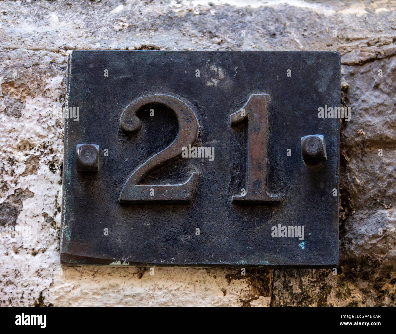 Bolted into the stone wall is an iron plaque with the number 21 Stock Photo