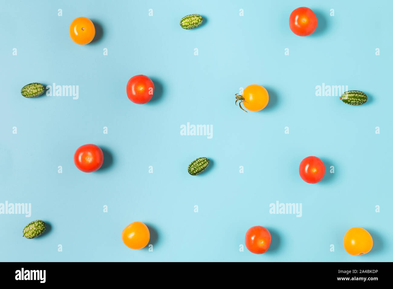Colorful food pattern of mini cucumbers and yellow and red tomatoes on blue background. flat lay. top view Stock Photo