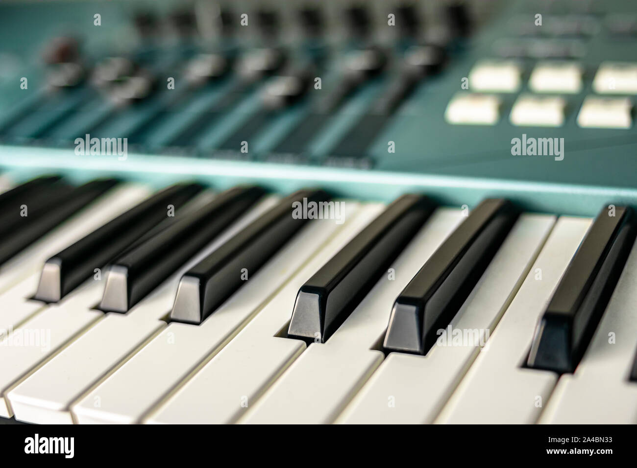Close-up of the natural and sustained keys of a stage keyboard or piano, along with control keypads and faders Stock Photo