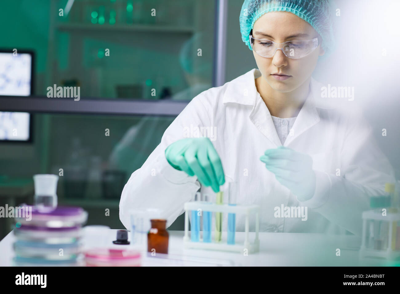 Portrait of young woman taking test tube with colored liquid while working on research in medical laboratory, copy space Stock Photo
