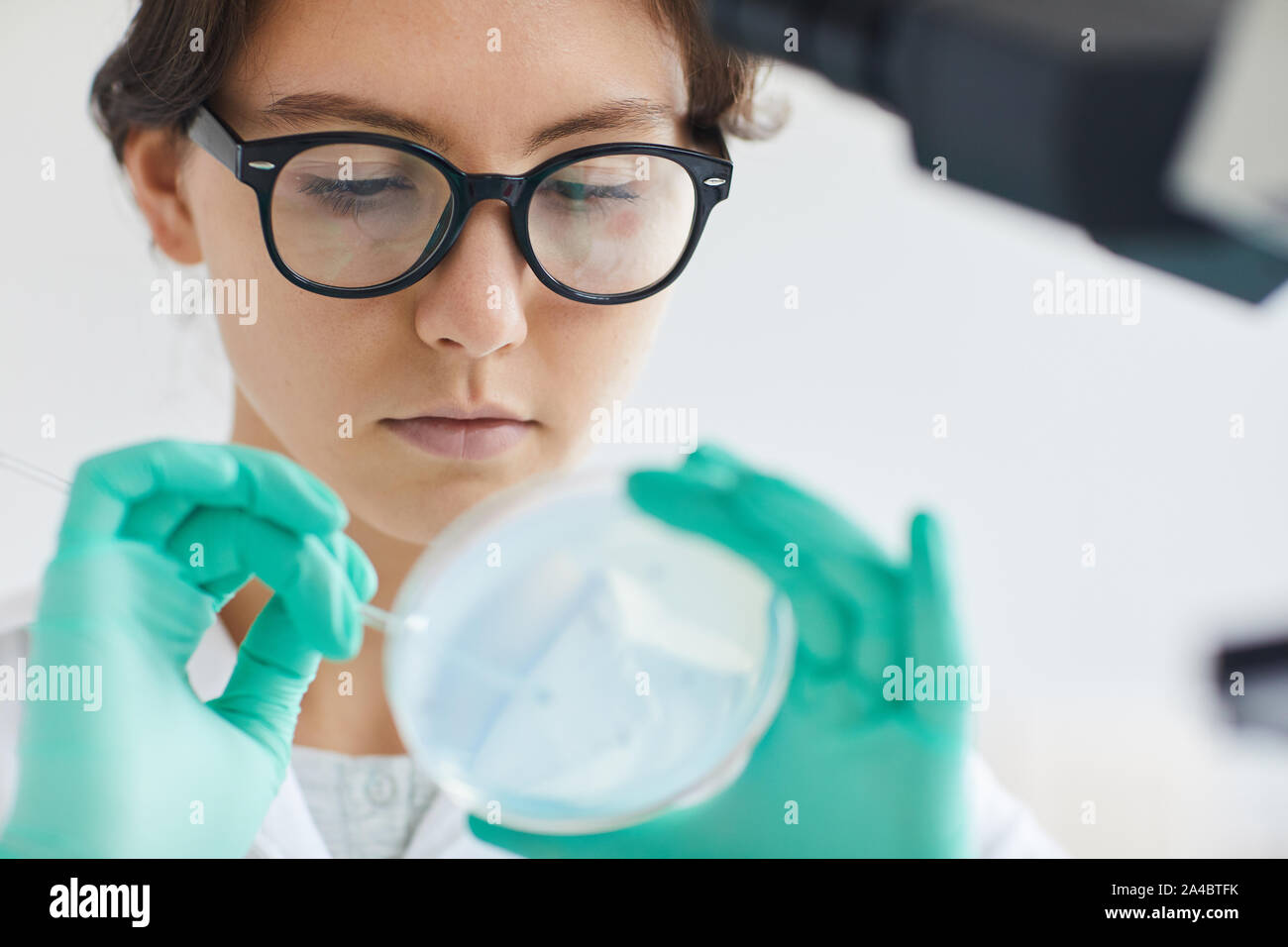 Close up portrait of beautiful young woman holding petri dish while working on research in medical laboratory, copy space Stock Photo