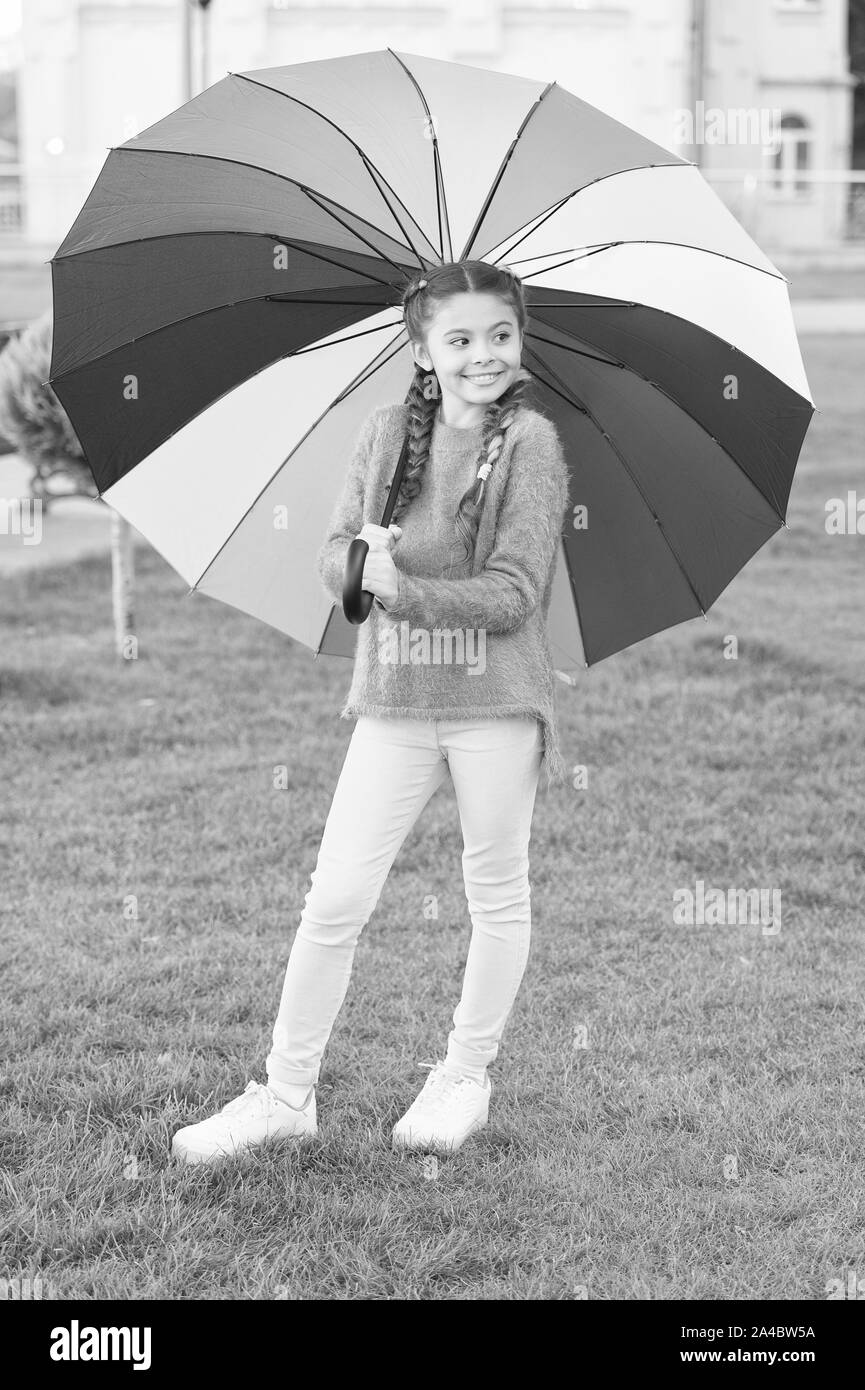 umbrella for little happy girl. Rainbow after rain. cheerful child. Spring style. Positive mood in autumn rainy weather. Little girl protected with colorful umbrella. Feeling protected at rainy day. Stock Photo