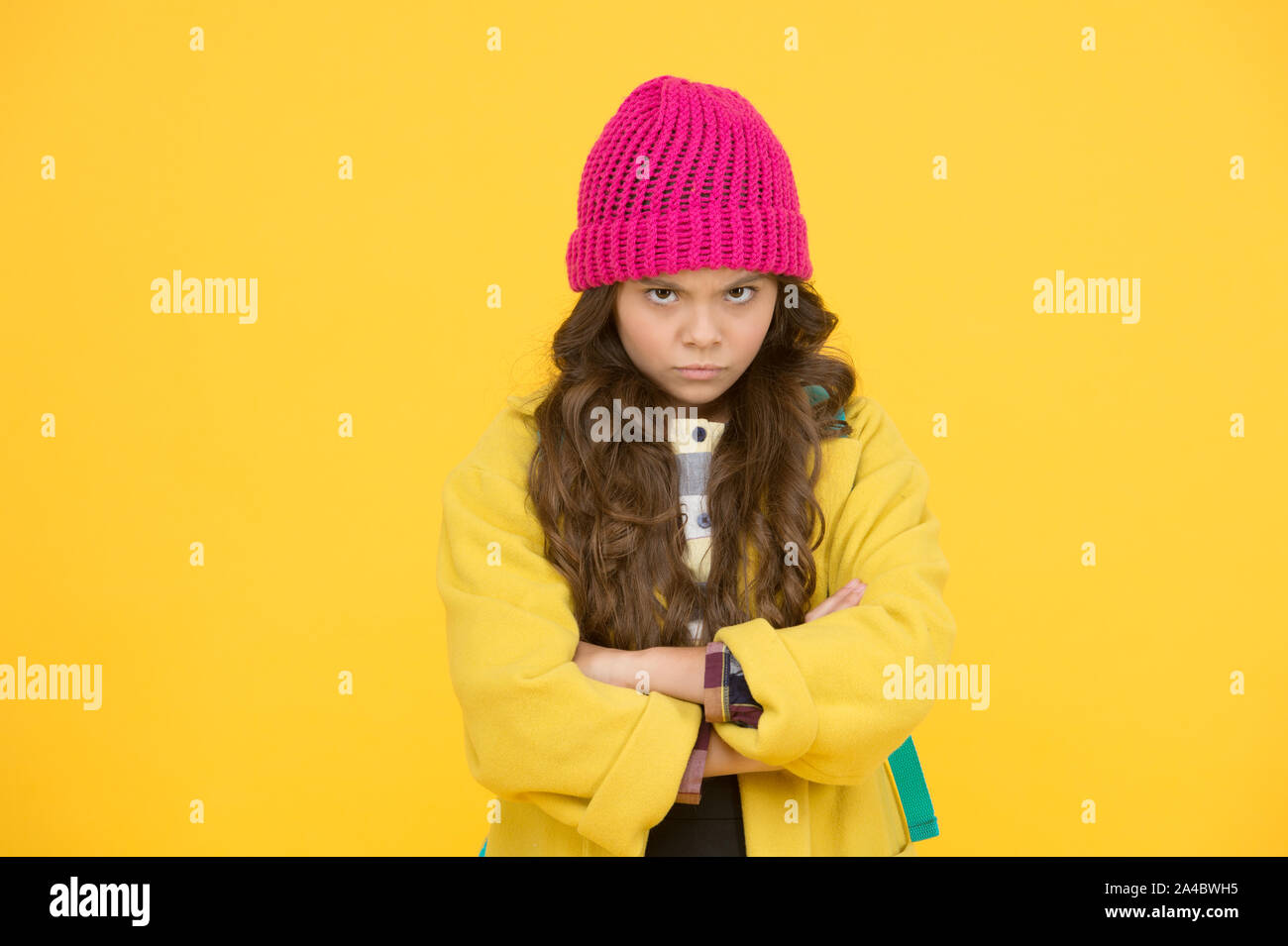 I hate school. Unhappy child on yellow background. Cute little child wear formal school uniform. Adorable small girl with long curly hair in autumn fashion. Child say no to school. Stock Photo