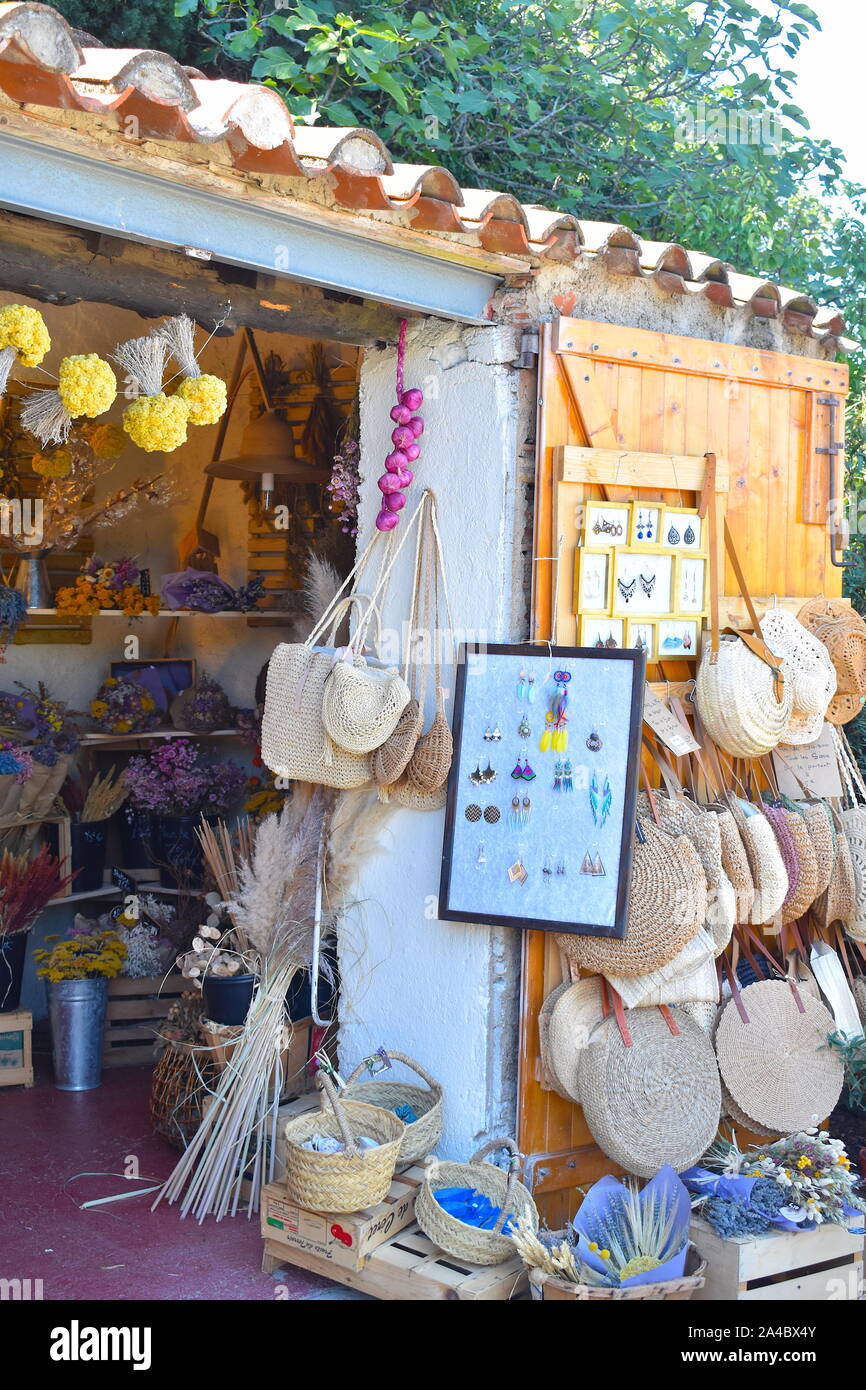 Dried colourful exotic flowers, lavender, herbs, pink garlic, earrings and straw tote bags on sale. Typical souvenir stall in south of France. Stock Photo