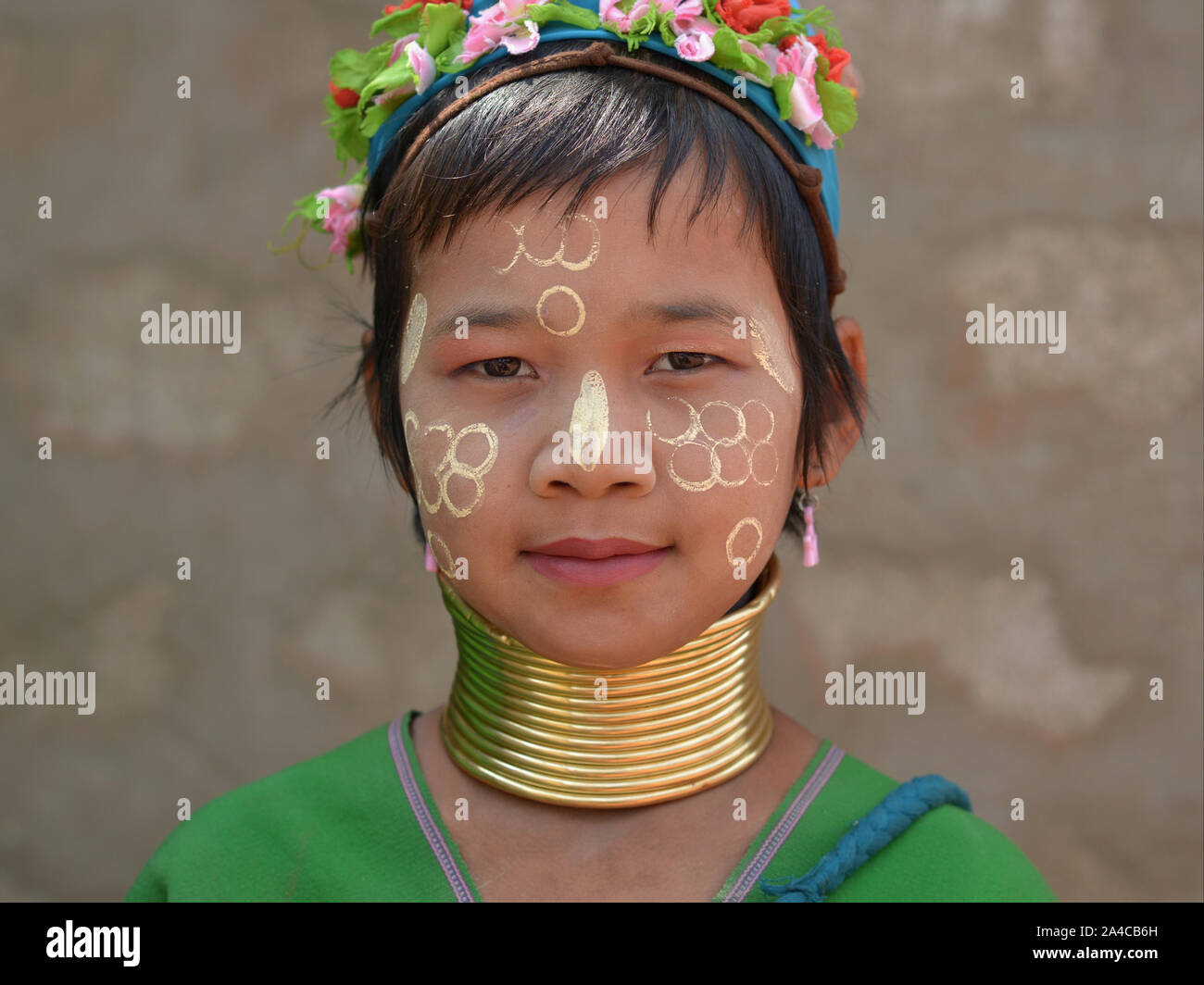 Myanmarese Kayan Lahwi girl with tribal brass neck rings/coils and traditional Burmese thanaka face cosmetic on her face poses for the camera. Stock Photo