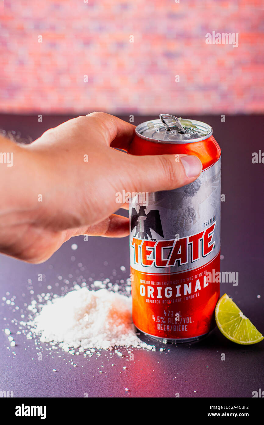 Person holding a Tecate beer can with salt and limes on the side on a vertical view Stock Photo