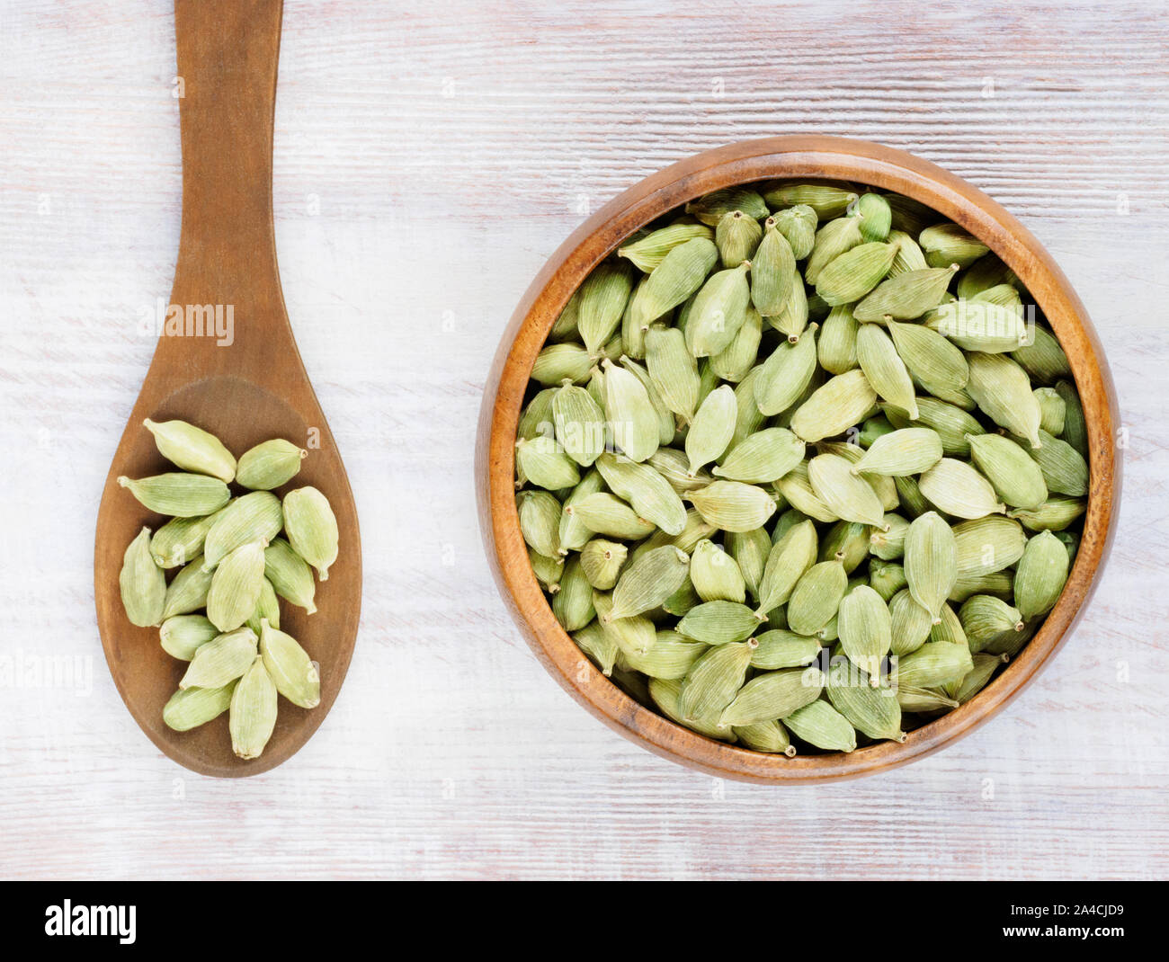 Spice Green cardamom (Elettaria cardamomum) in a wooden cup and spoon on a white wooden background Stock Photo