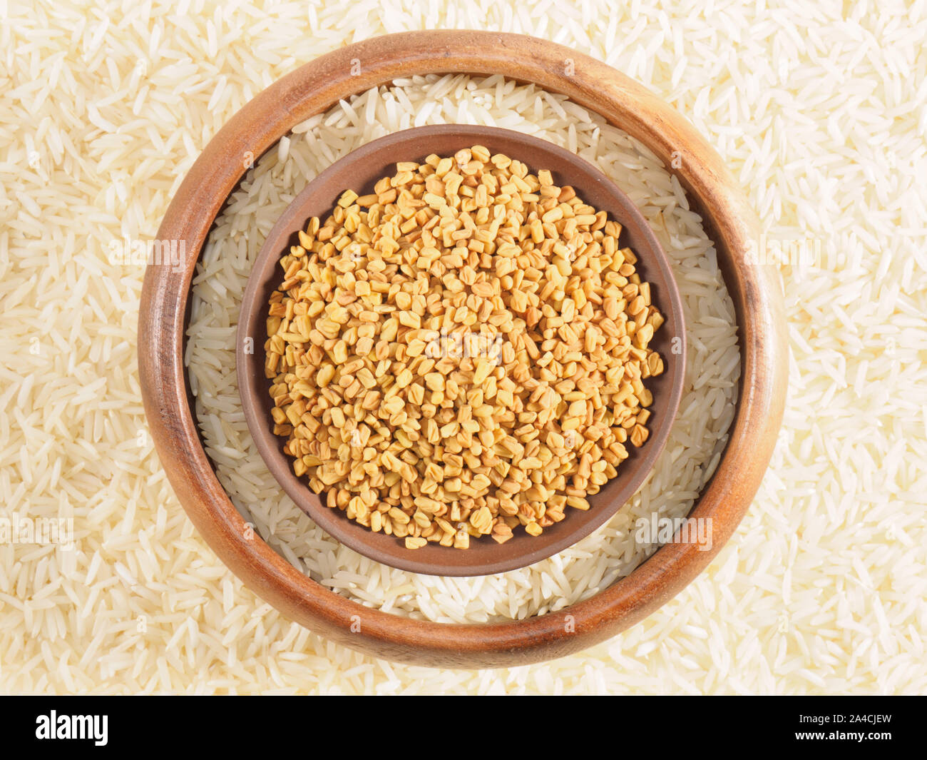 Rice in bowl and fenugreek in clay, plate. Background from basmati rice. Indian cuisine ingredients Stock Photo