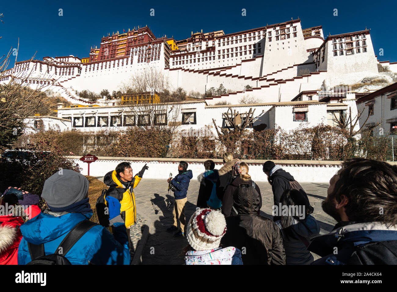 Lhasa, China - December 13 2018: International tourists listen to their tour guide about the Potala Palace in the heart of Lhasa old town in Tibet pro Stock Photo