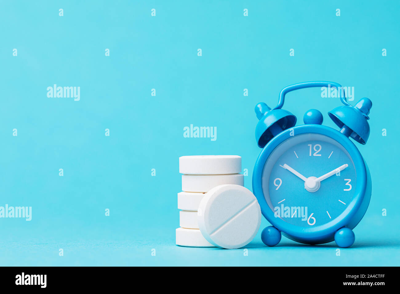 Pills and alarm clock on a blue background with copy space. Its time to