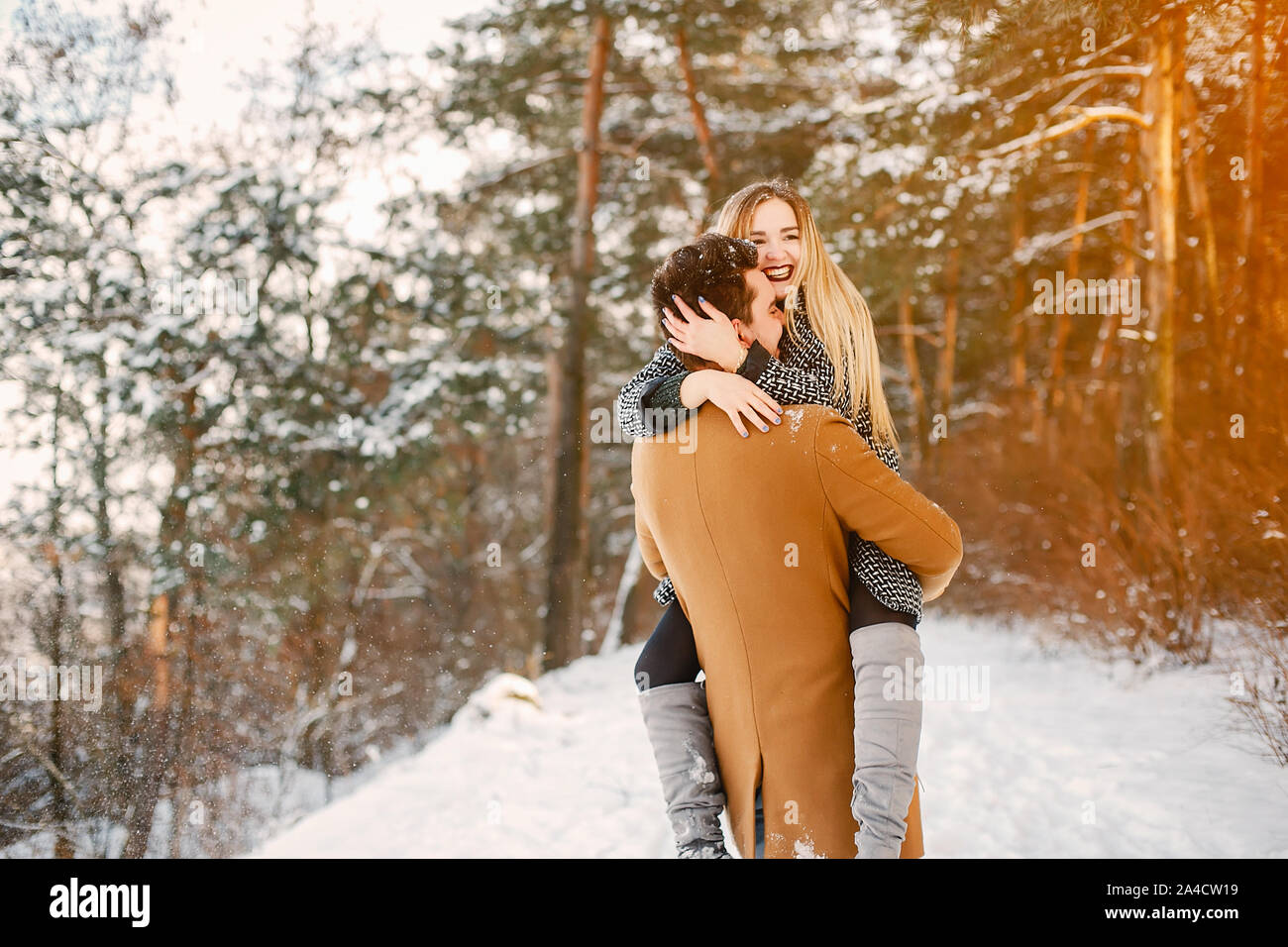 happy couple hugging and kissing in the park on a snowy winter day ...