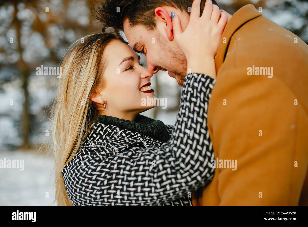 happy couple kissing and hugging in the park on a snowy winter day ...