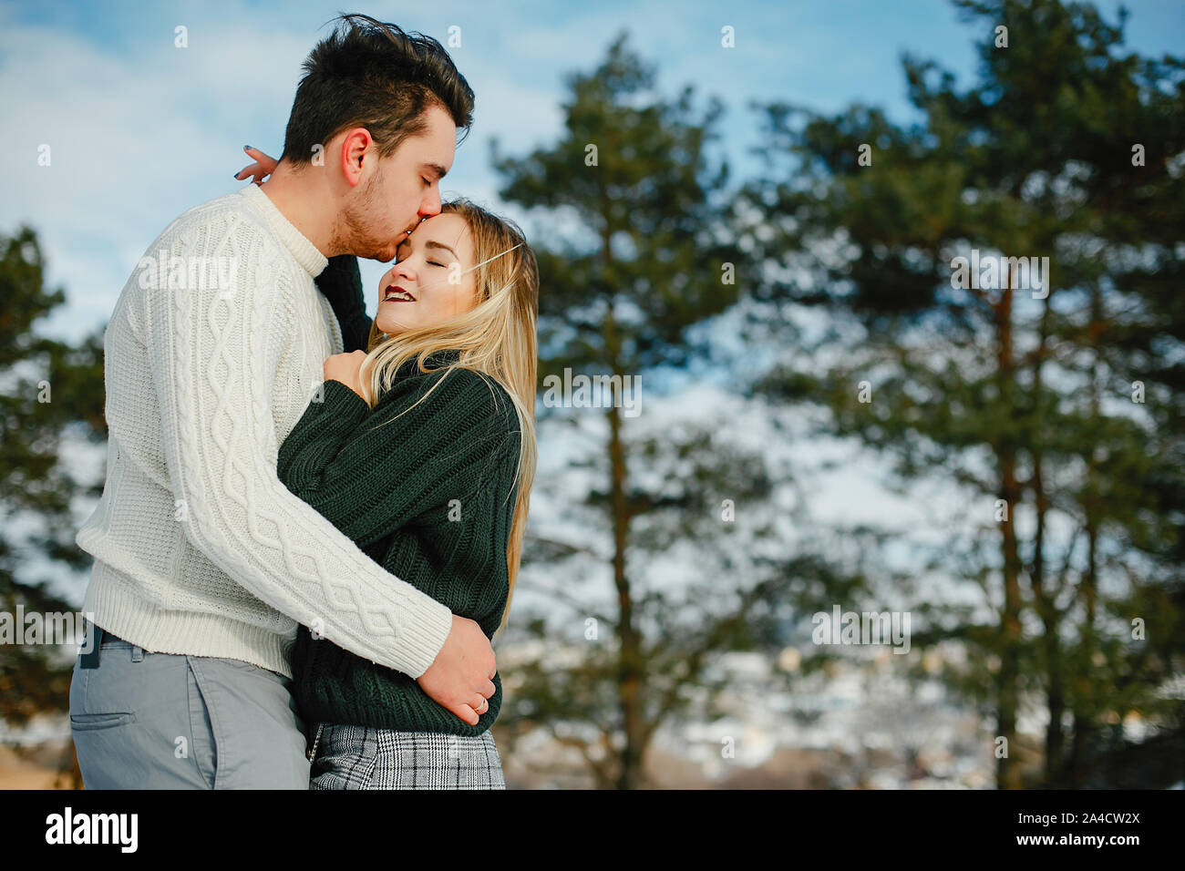 happy couple kissing and hugging in the park on a snowy winter day ...
