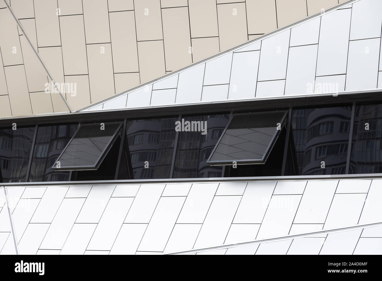 Outside view on white tiled wall of building with few black tinted