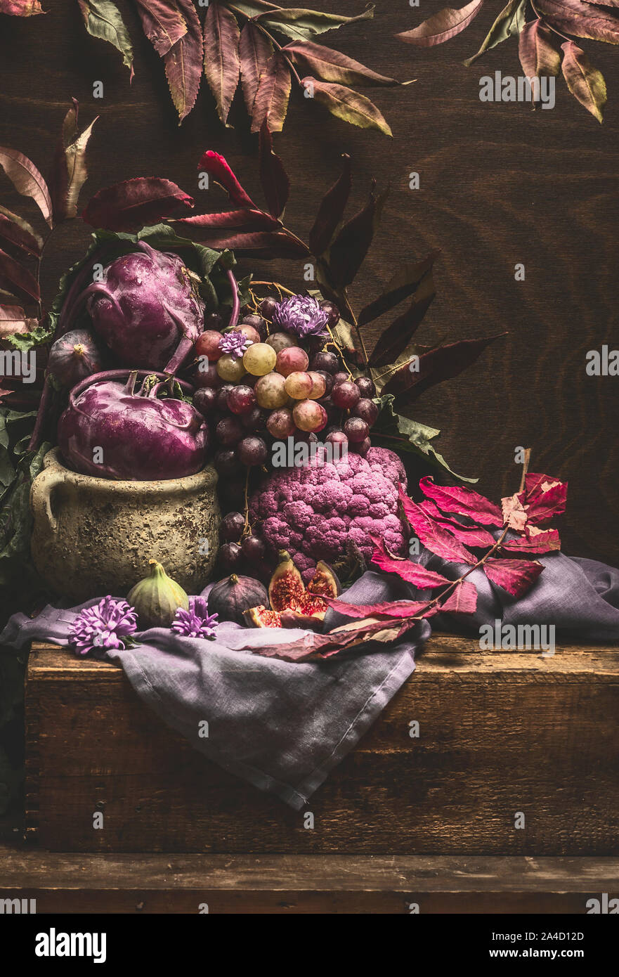 Still life with purple fruits and vegetables on wooden table with ...