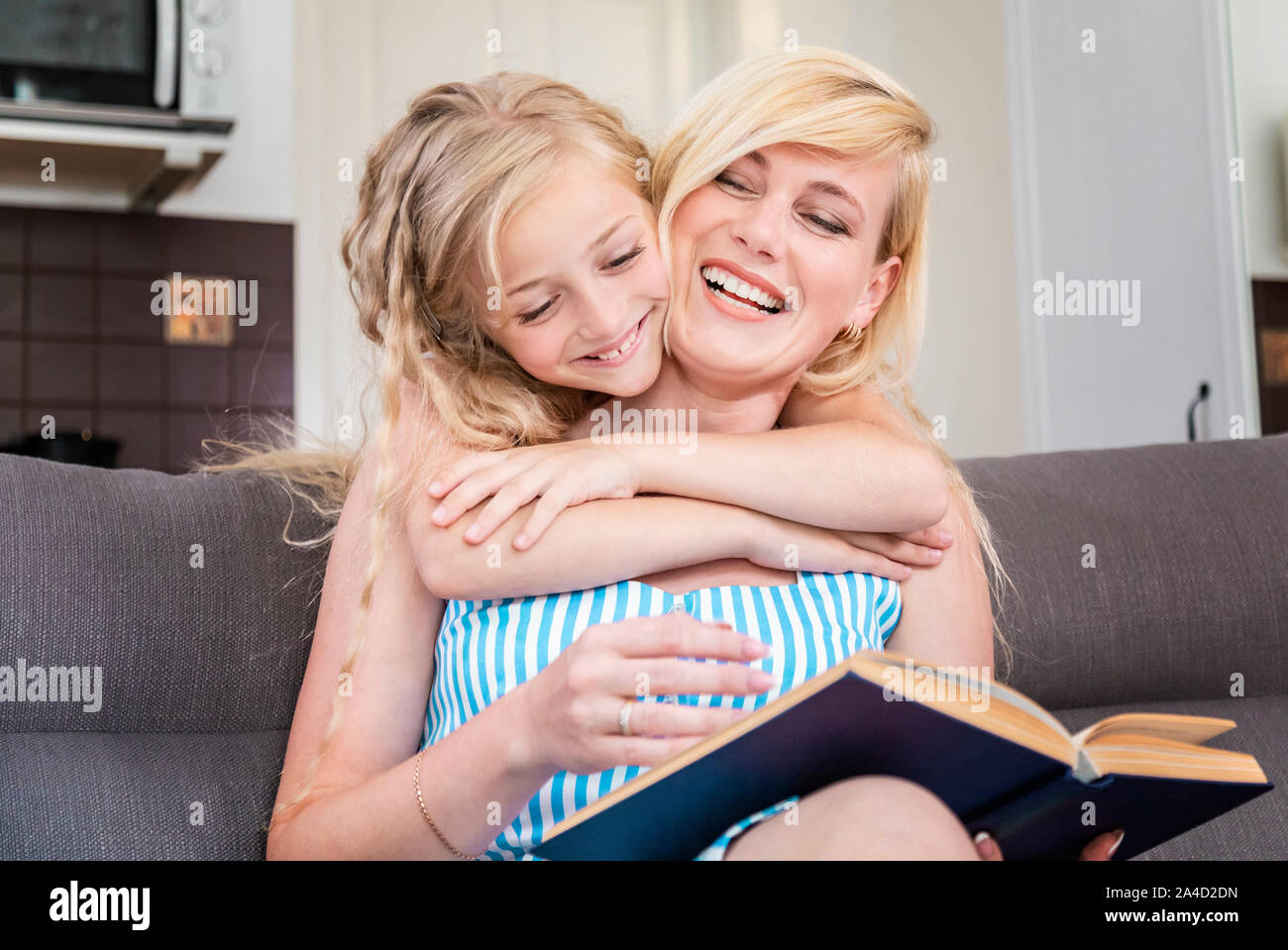 Young mother and her little princess enjoy spending spare time reading in a living room Stock Photo