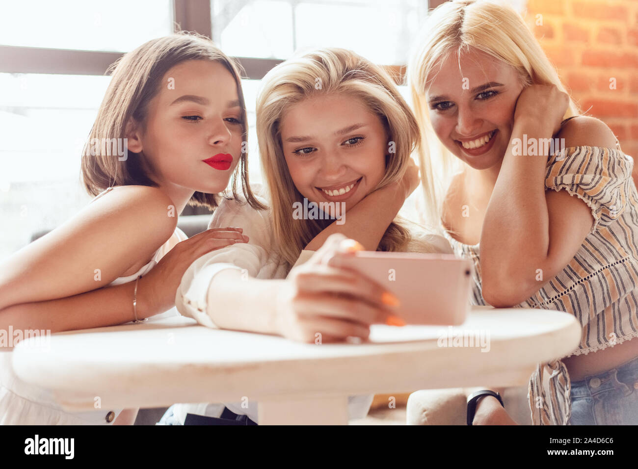 Beautiful girls sitting in a cafe and make selfie Stock Photo - Alamy