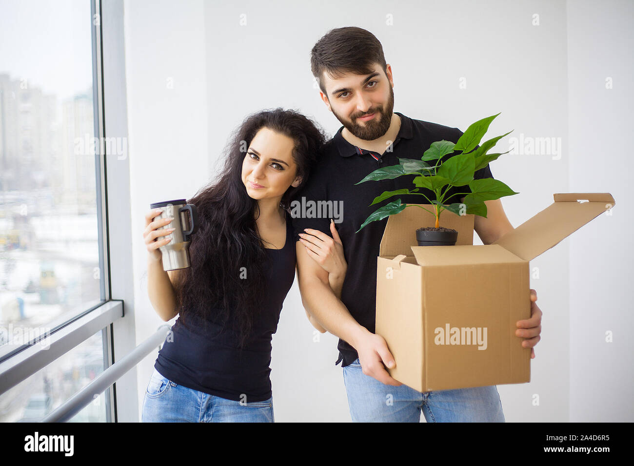 Couple showing keys to new home hugging looking at camera Stock Photo ...