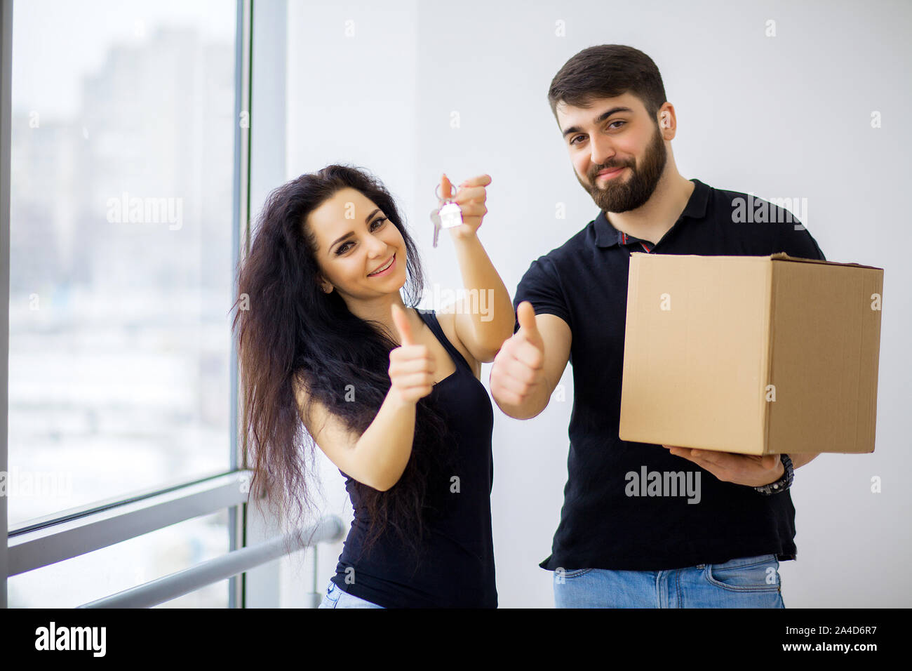 Couple showing keys to new home hugging looking at camera Stock Photo ...