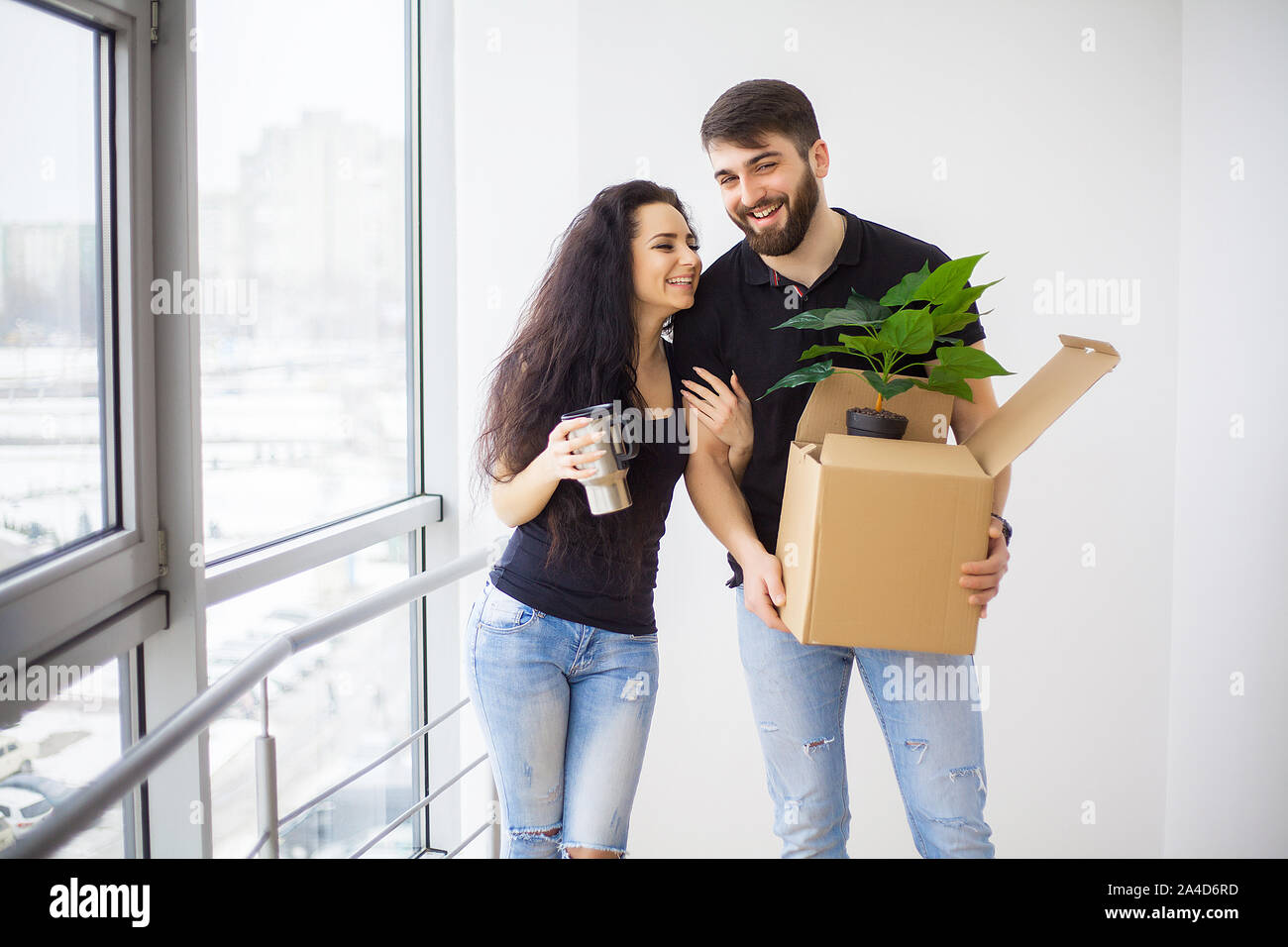 Couple showing keys to new home hugging looking at camera Stock Photo ...