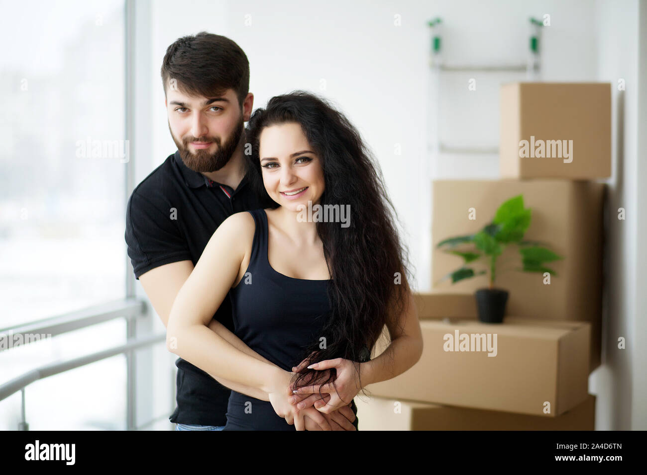 Couple showing keys to new home hugging looking at camera Stock Photo ...