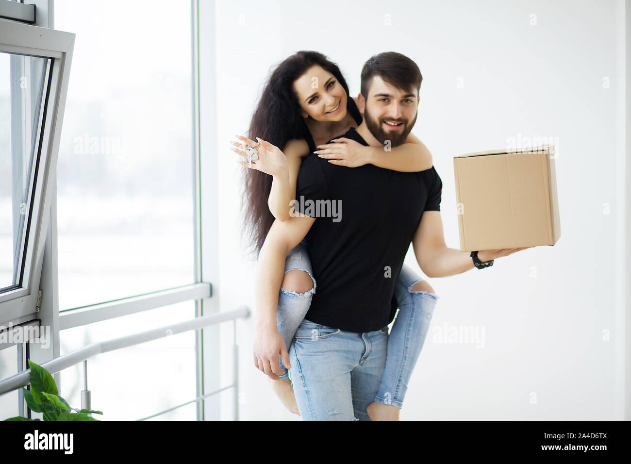 Couple showing keys to new home hugging looking at camera Stock Photo ...