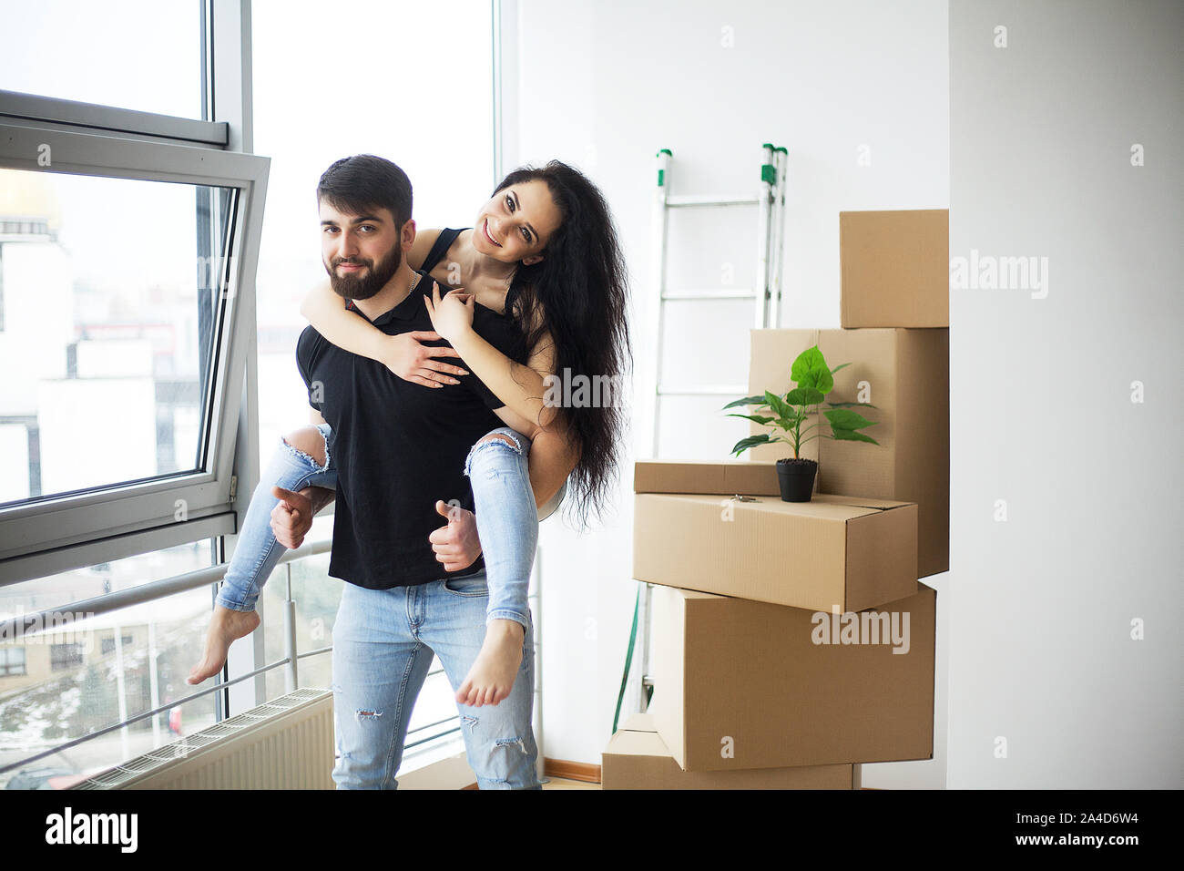 Couple showing keys to new home hugging looking at camera Stock Photo ...