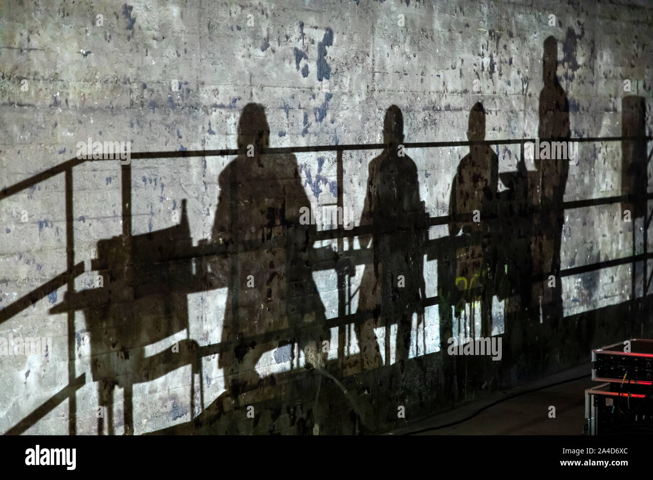 Shadows of participants of an event sitting on a stage and discussing on a wall, Stock Photo