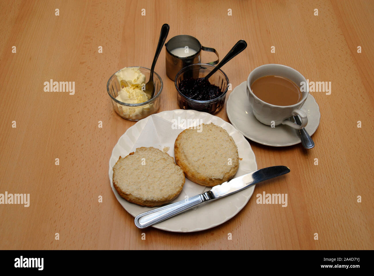 Traditional cream tea with large scone cut in two before the addition of clotted crea and raspberry jam Stock Photo