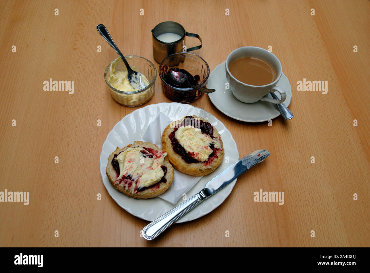 Traditional cream tea with large scone cut in two, with raspberry jam and clotted cream on both halves Stock Photo