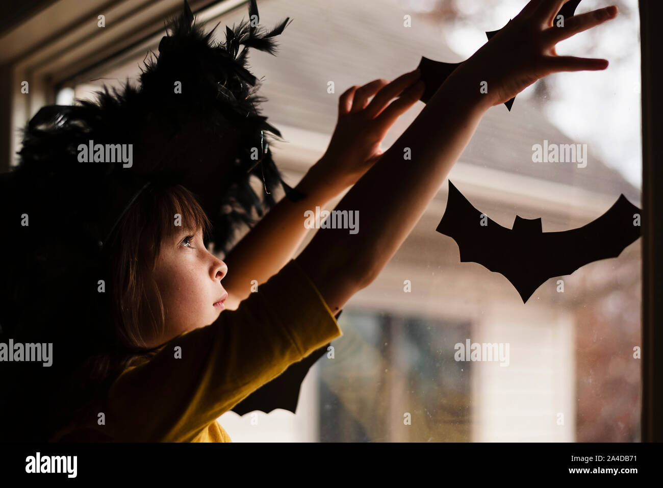 Girl in a witch's hat putting up Halloween decorations Stock Photo - Alamy