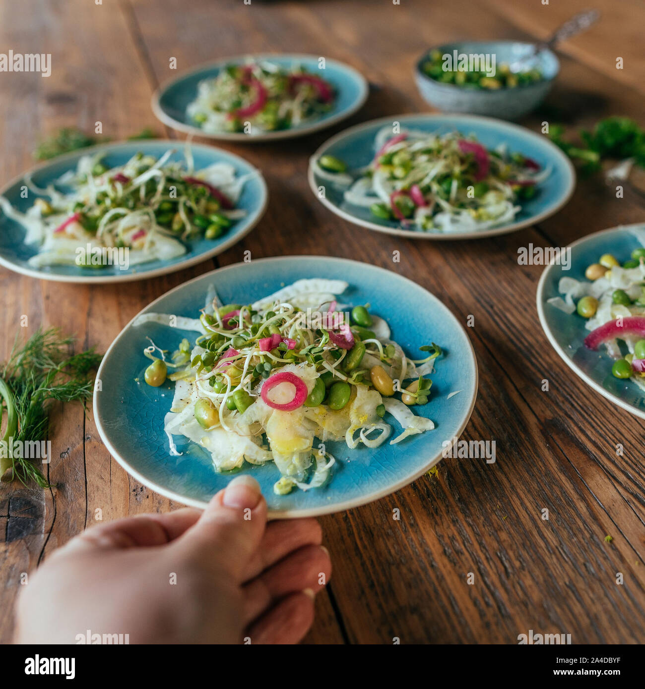 Woman serving plates of radish salad Stock Photo