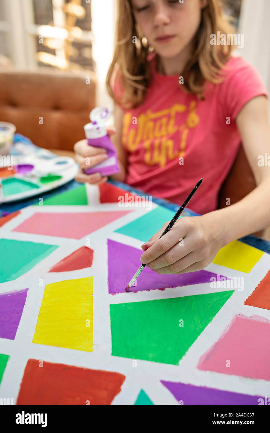 Girl sitting at a table painting Stock Photo