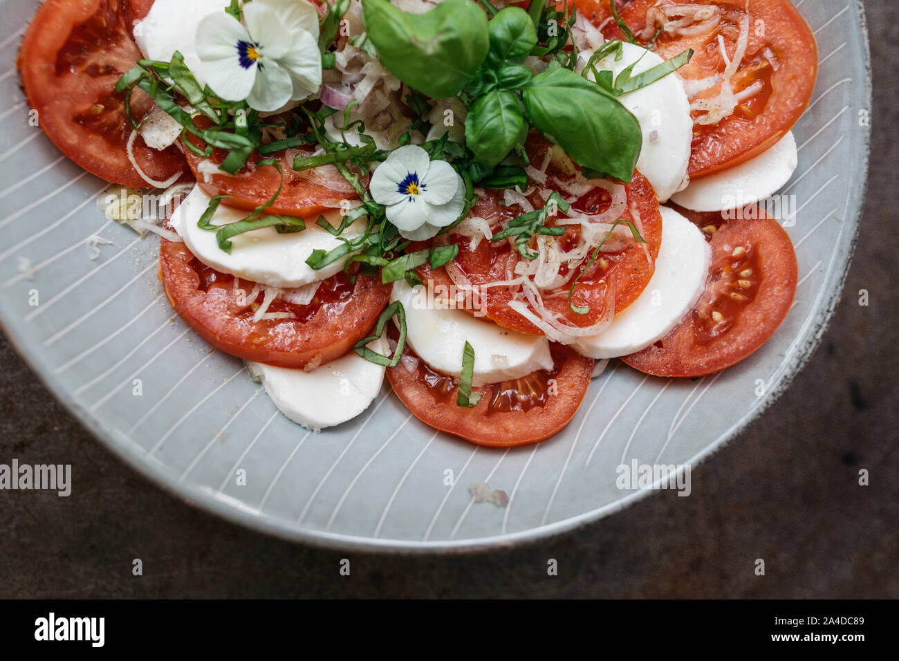 Mozzarella, tomato and basil salad with edible violets Stock Photo