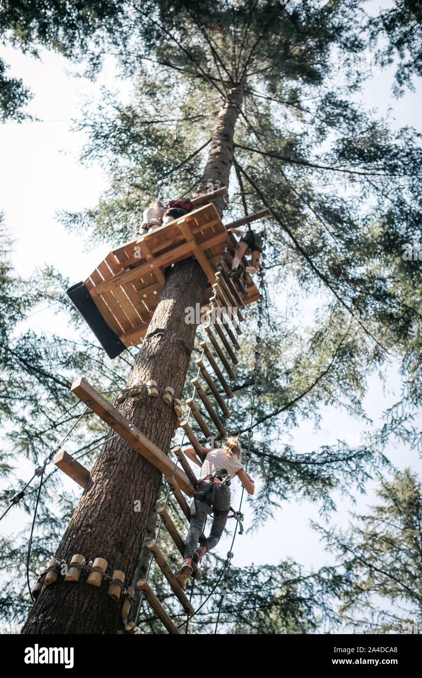 Low angle view of a girl climbing a rope ladder up to a platform Stock Photo
