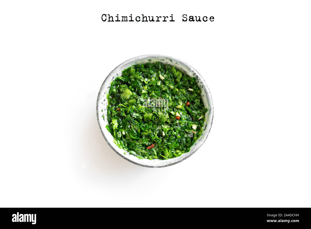 Raw homemade chopped green Chimichurri or Chimmichurri sauce made of parsley, garlic, oregano, hot pepper, olive oil, vinegar, isolated on white, top Stock Photo