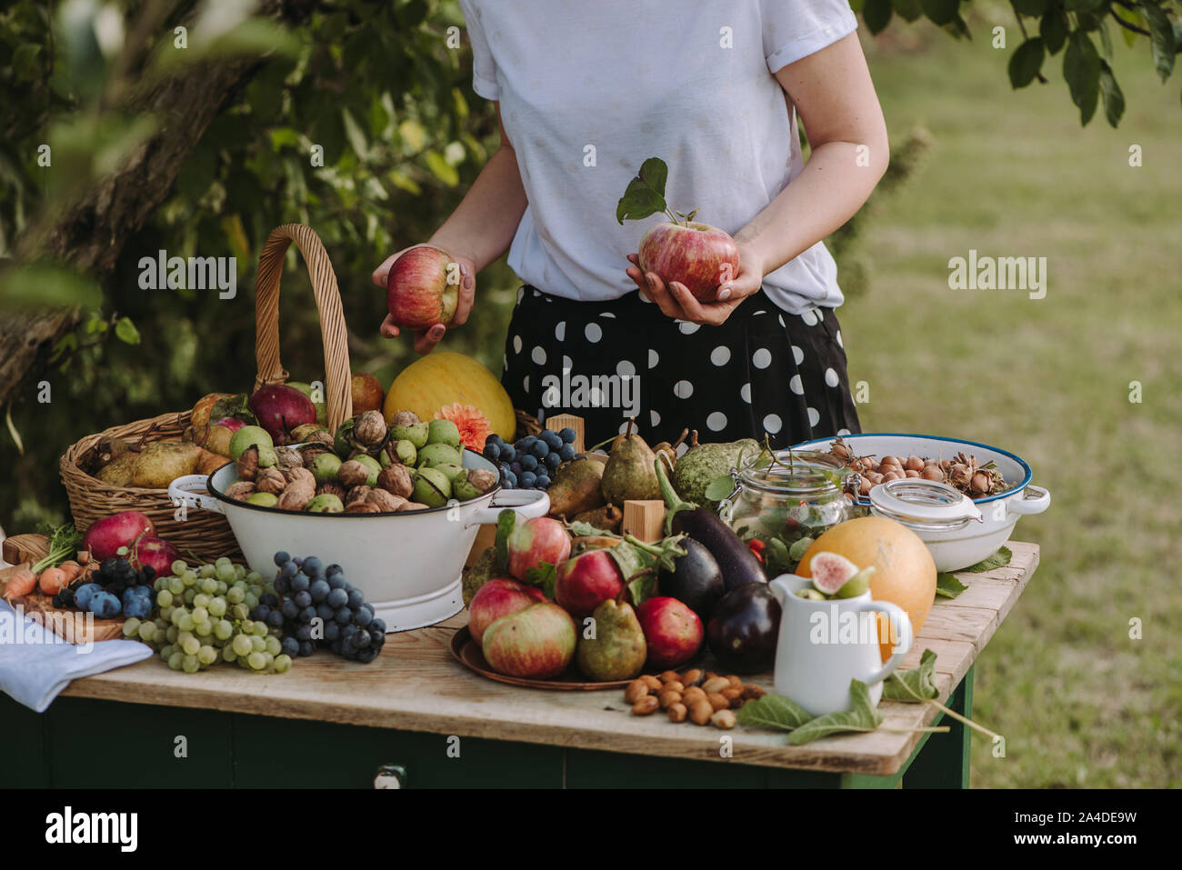 Woman standing by a table with fruit and vegetables holding apples, Serbia Stock Photo